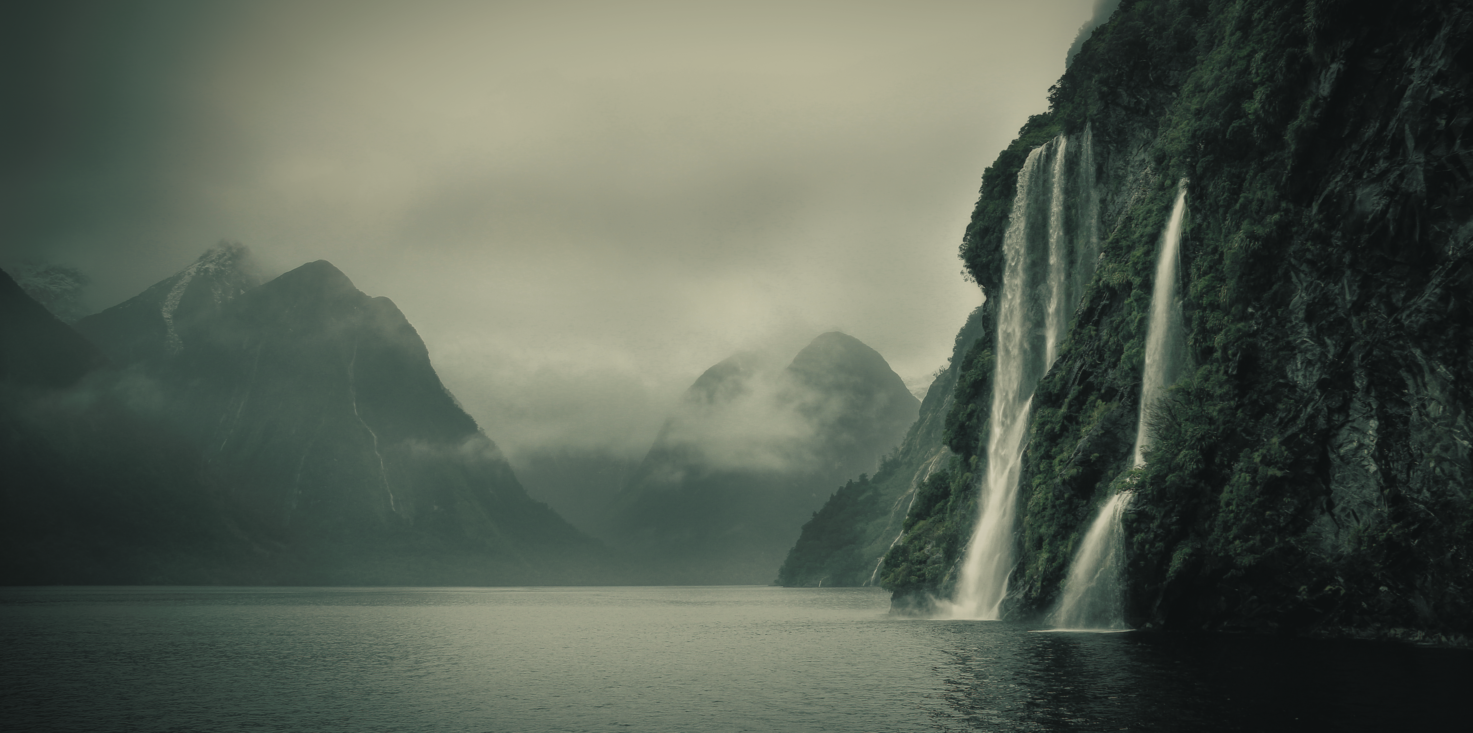 Stunning landscape with a waterfall cascading into a lake surrounded by mountains.